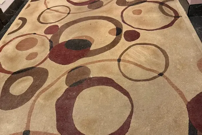 Wool area rug with a circle pattern showing soiled traffic areas before cleaning